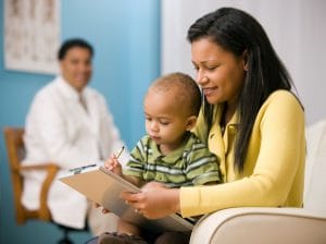 A woman with her child signing forms before their first allergist appointment.