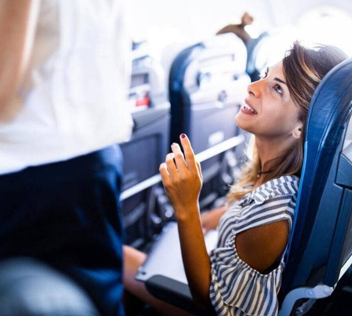 Female tourist talking to stewardess during a flight in a plane.