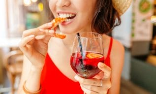 Do Antacids or Alcohol Trigger Shellfish Allergy in Adults?. Happy woman in hat eating local Spanish cuisine grilled seafood.