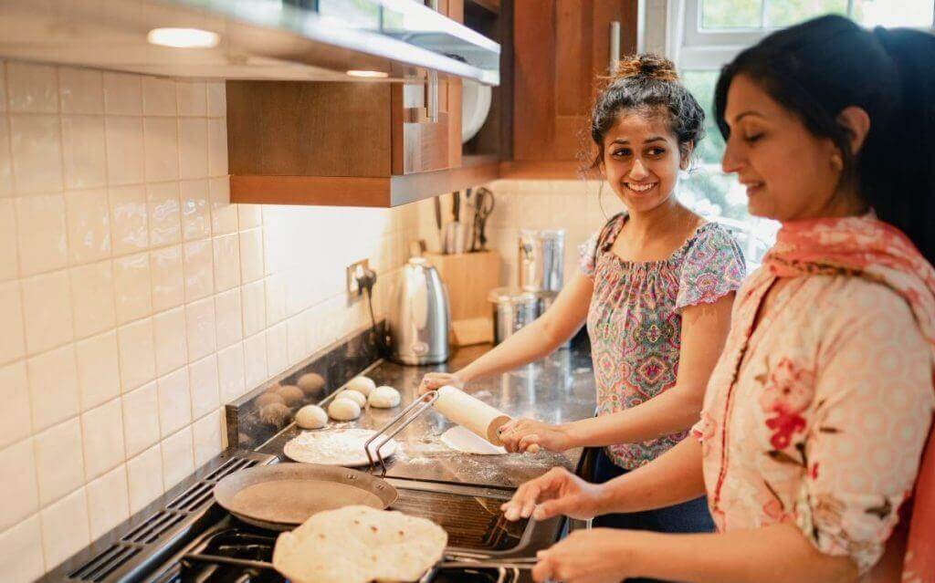 Teen and grandmother cooking together in the kitchen.