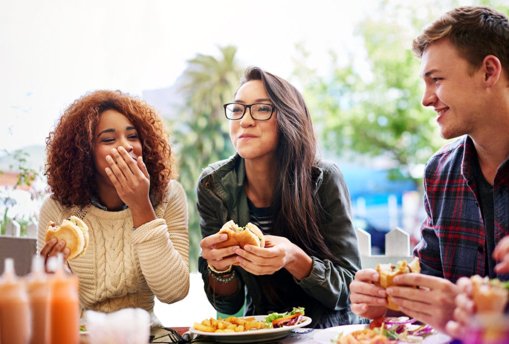 Cropped shot of three friends eating burgers