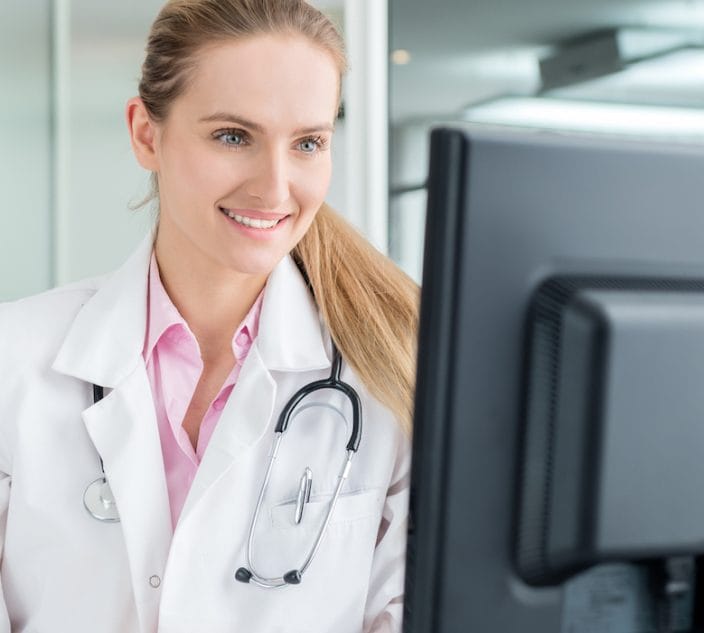 Doctor looking at computer monitor, speaking with patients.