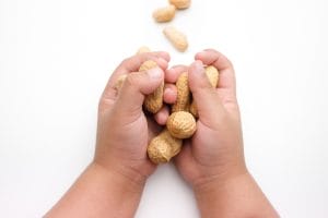 Child's hands holding shelled peanuts. How can you tell if a peanut reaction is a severe allergy of just part of OAS. 